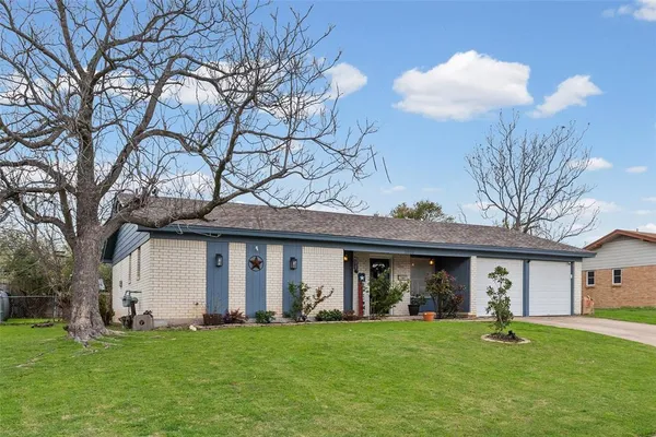 a view of a brick house with a big yard and large trees