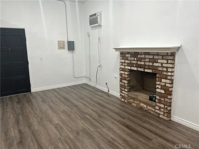 an empty room with wooden floor fireplace and windows