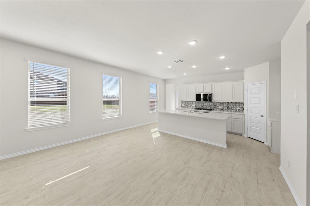 125 Pheasant Run Road Terrell, TX 75160 - Photo 10 of 27 a large white kitchen with kitchen island a sink dishwasher and white cabinets with wooden floor