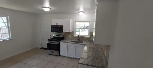 a kitchen with granite countertop a stove top oven microwave and refrigerator