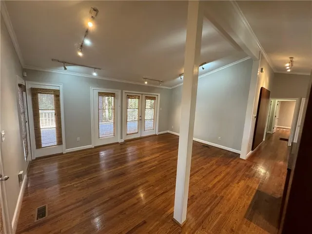 a view of an empty room with wooden floor and a window