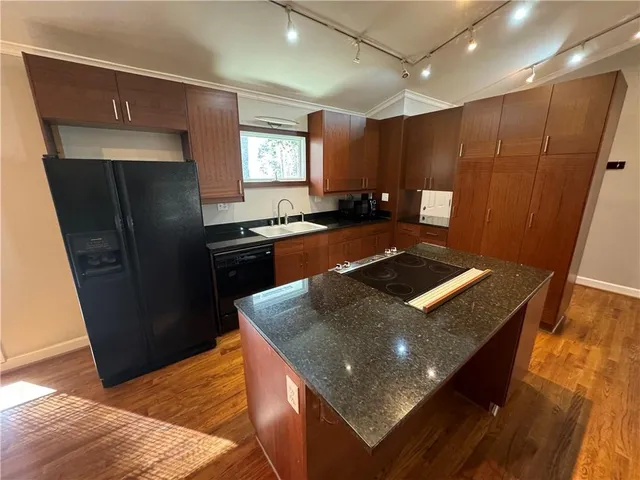 a kitchen with stainless steel appliances granite countertop a refrigerator a stove and a sink with wooden floor
