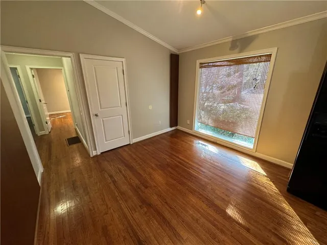 a view of an empty room with wooden floor and a window