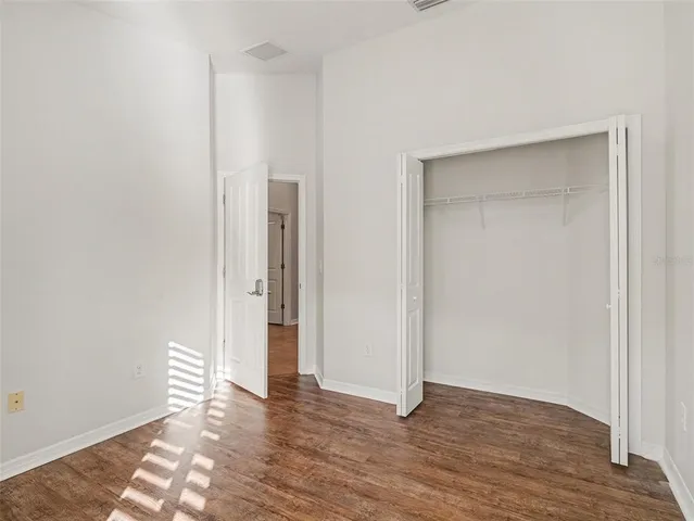 a view of an empty room with wooden floor and closet
