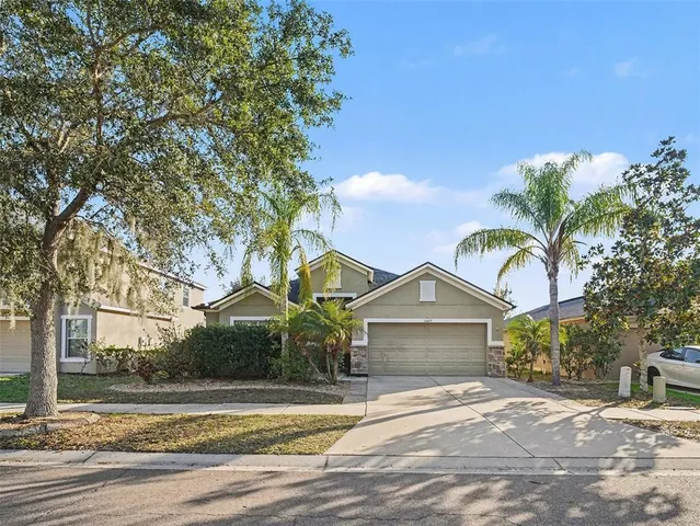 a view of a house with a yard and large tree