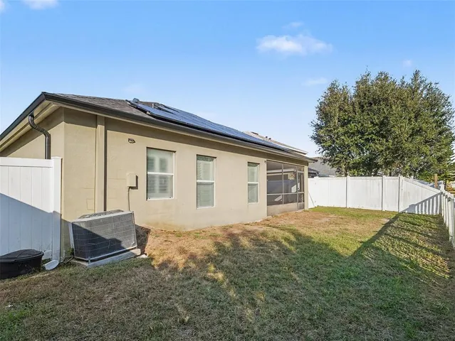 a backyard of a house with large trees and wooden fence