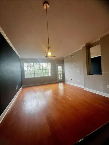 a view of an empty room with a window and wooden floor