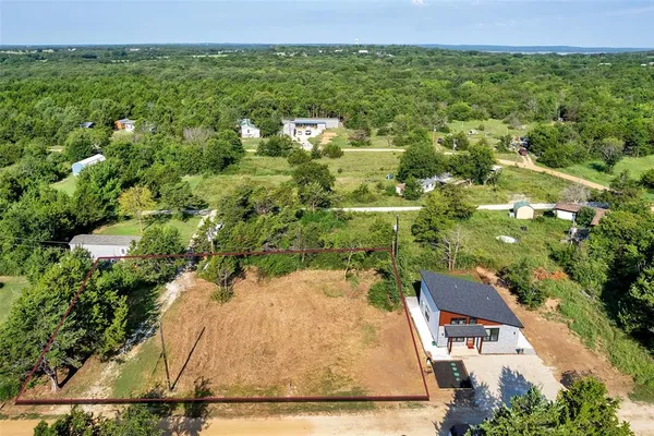 an aerial view of residential houses with outdoor space and trees