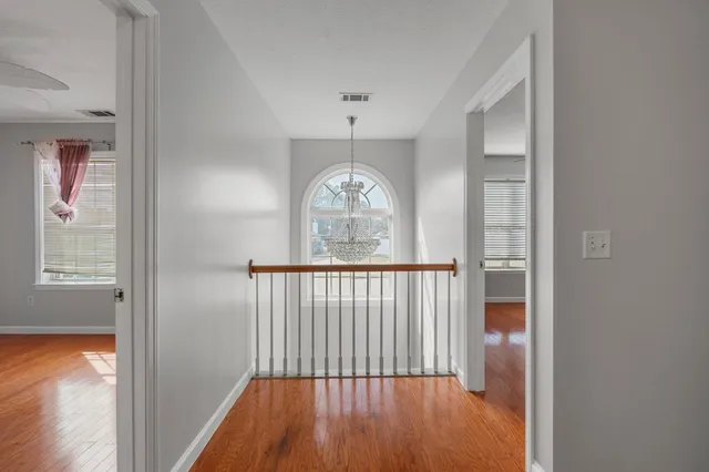 a view of a hallway with wooden floor and a chandelier