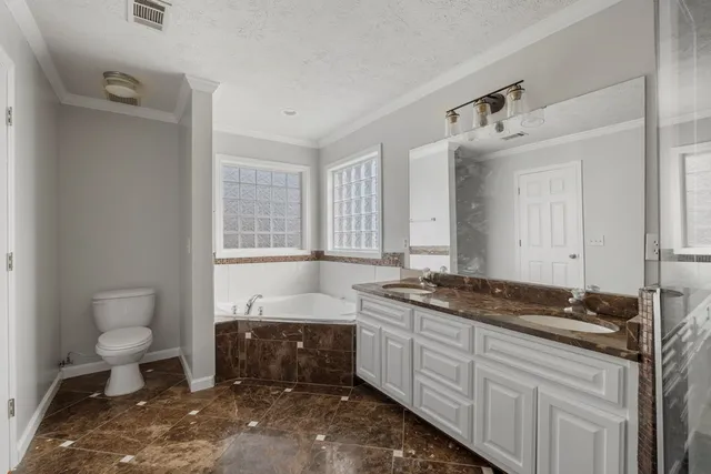 a spacious bathroom with a granite countertop sink a toilet and a bathtub