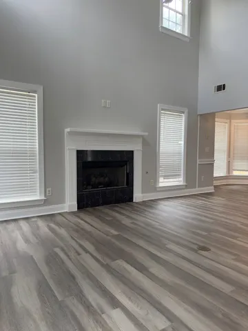 a view of an empty room with wooden floor fireplace and a window