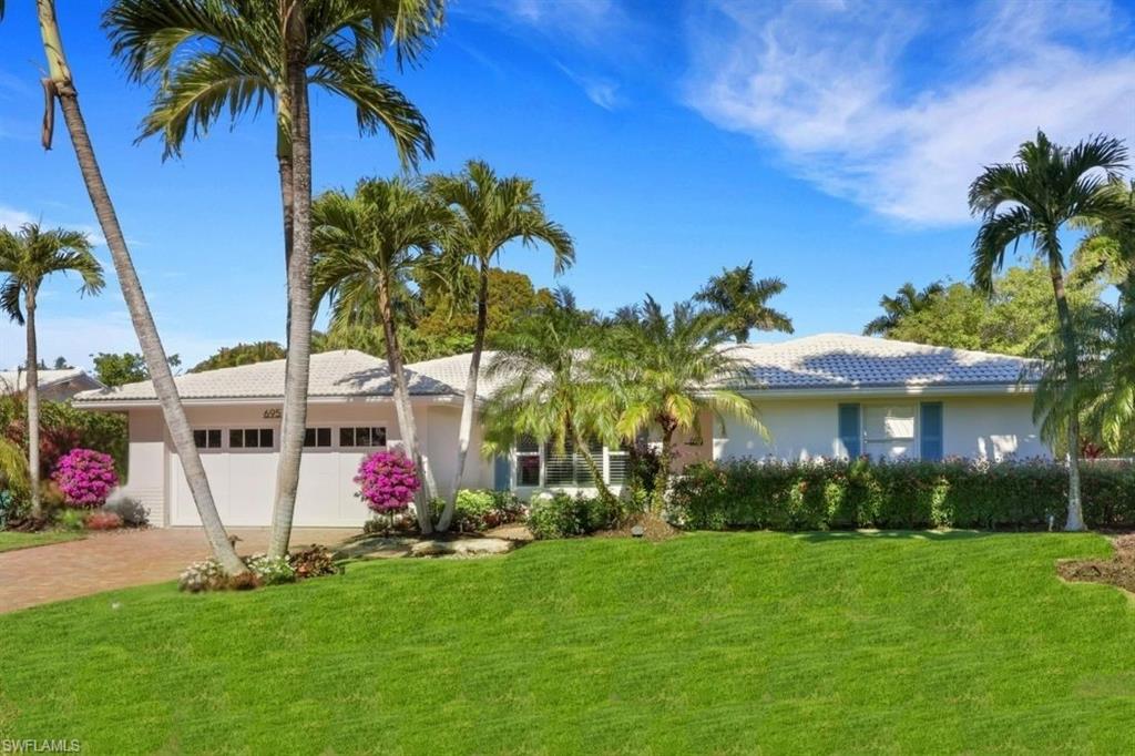View of front facade featuring a front yard, an attached garage, driveway, and stucco siding