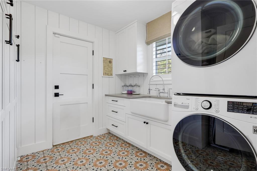 695 Regatta Road Naples, FL 34103 - Photo 12 of 43 Washroom with stacked washing machine and dryer, cabinet space, and light tile patterned floors