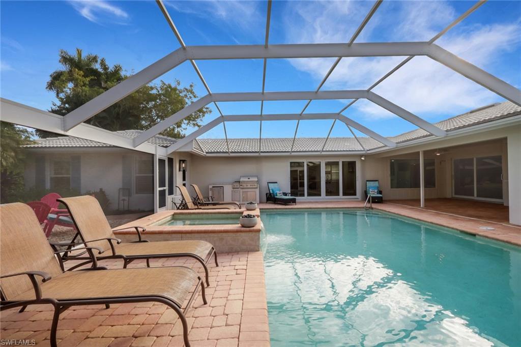 695 Regatta Road Naples, FL 34103 - Photo 31 of 43 View of pool featuring a sunroom, a pool with connected hot tub, grilling area, and glass enclosure