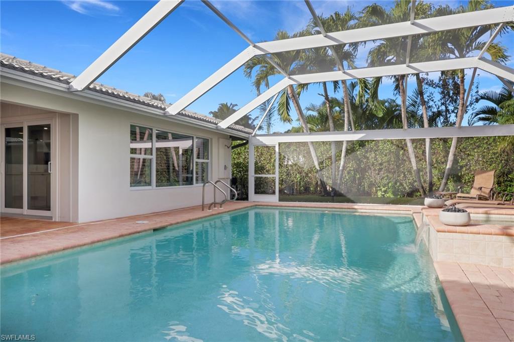 695 Regatta Road Naples, FL 34103 - Photo 32 of 43 Outdoor pool featuring a sunroom, a patio, glass enclosure, and an outdoor fire pit