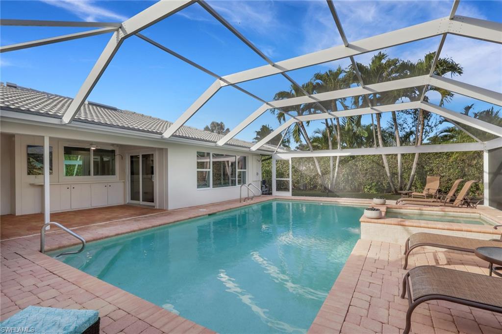 695 Regatta Road Naples, FL 34103 - Photo 33 of 43 Swimming pool with a sunroom, an in-ground hot tub, a patio area, and a lanai
