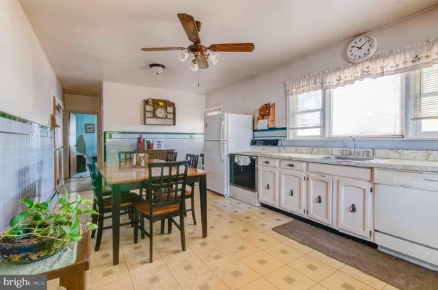 a open kitchen with stainless steel appliances granite countertop a stove a sink a dining table and chairs with wooden floor