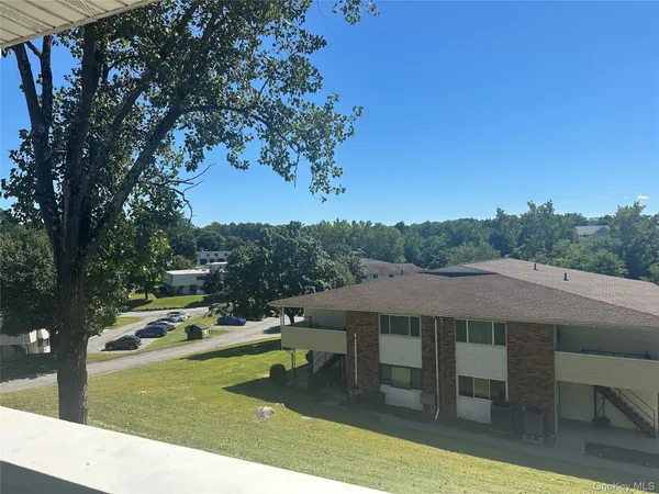 an empty room with wooden floor and kitchen view