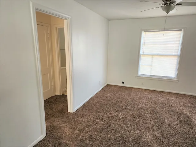 an empty room with a window and a ceiling fan