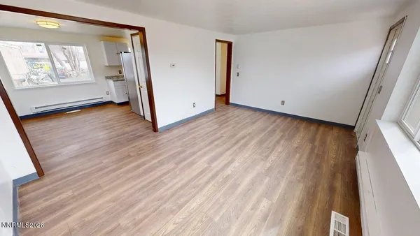 an empty room with wooden floor and windows