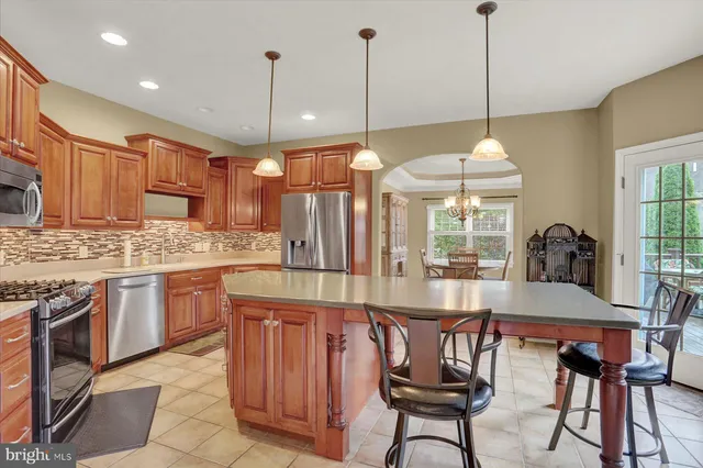 a view of a kitchen with kitchen island a stove a chandelier a dining table and chairs
