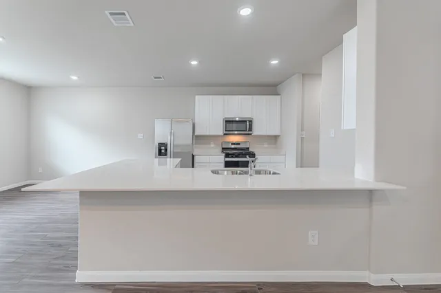 a kitchen with kitchen island a sink a stove a refrigerator and cabinets