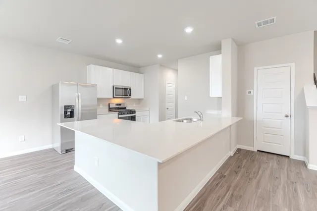 a large white kitchen with kitchen island a sink a stove and refrigerator