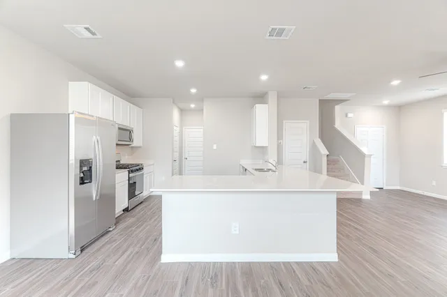a view of kitchen with stainless steel appliances refrigerator stove microwave and cabinets