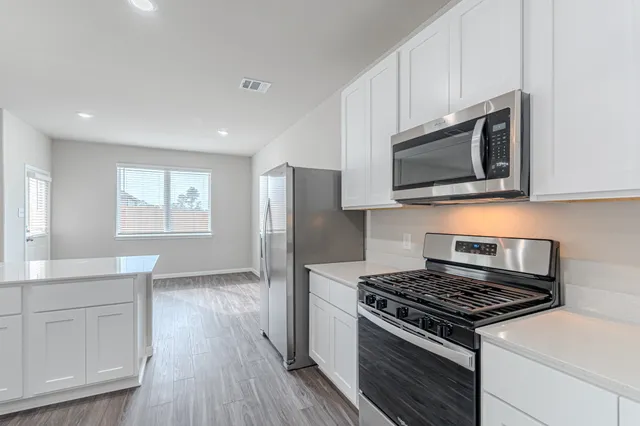 a kitchen with stainless steel appliances white cabinets and stove top oven