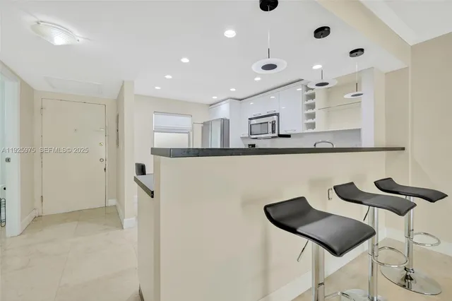 a kitchen with stainless steel appliances kitchen island granite countertop a refrigerator and a sink