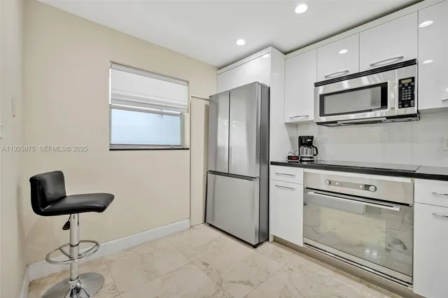 a kitchen with granite countertop a refrigerator a stove a microwave a dining table and chairs with wooden floor