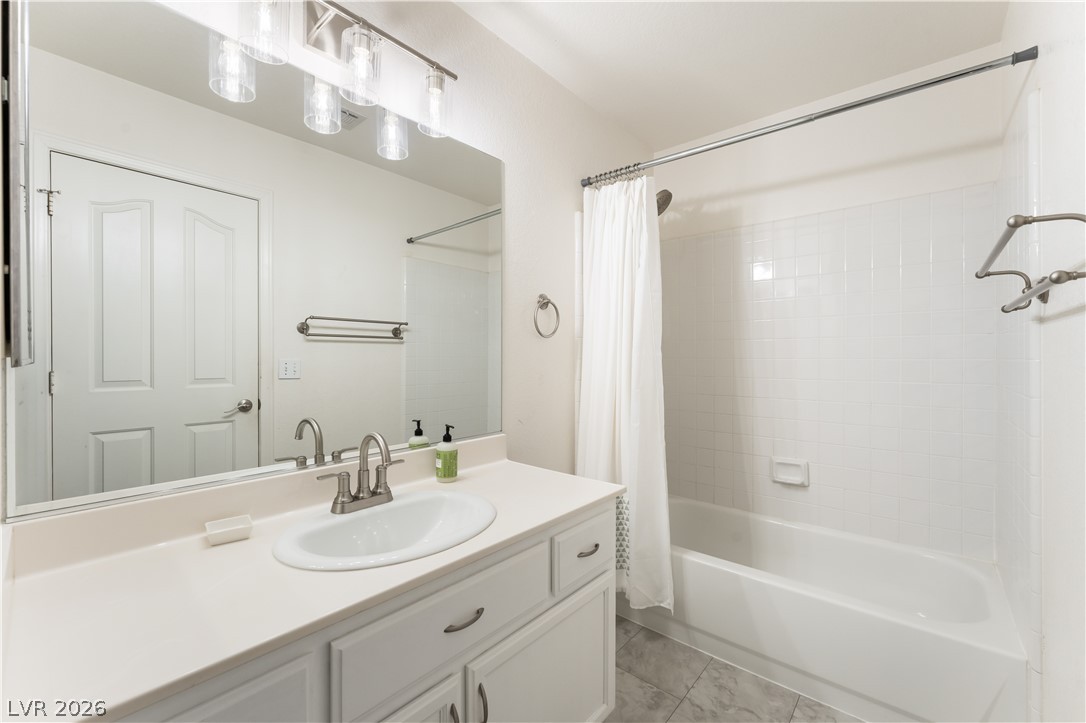 8872 Chapman Point Las Vegas, NV 89129 - Photo 21 of 29 A well-lit bathroom with a white vanity and a full-sized tub.