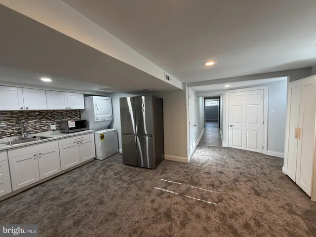 a large white kitchen with stainless steel appliances granite countertop a refrigerator and a stove top oven