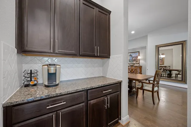a kitchen with granite countertop a table chairs stove and cabinets