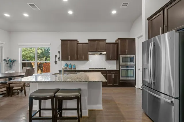 a kitchen with granite countertop a refrigerator and a stove top oven