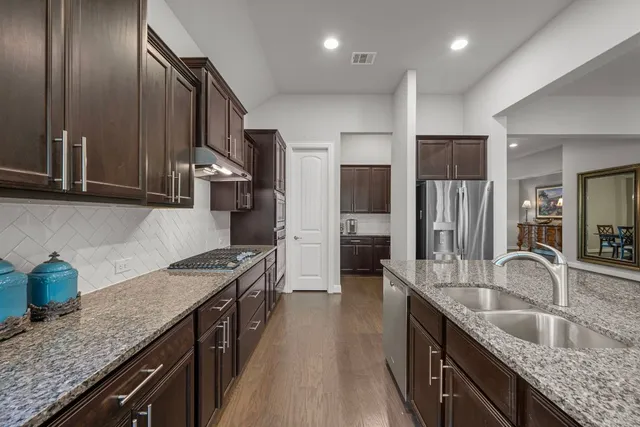 a kitchen with stainless steel appliances granite countertop a sink a stove and a refrigerator