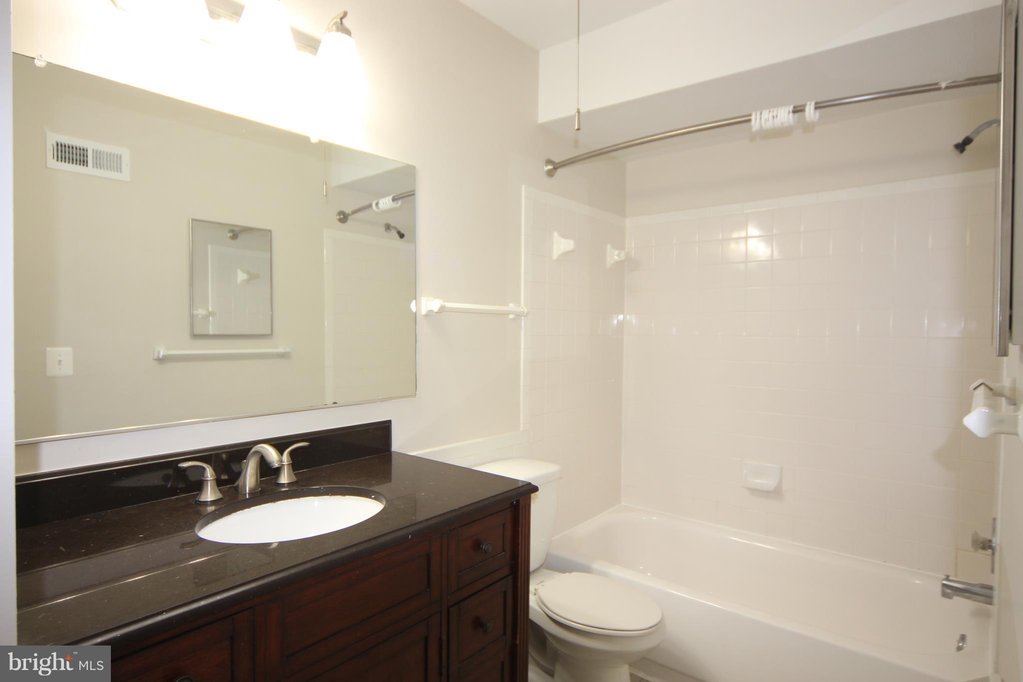 5903 Kingsford Road, Unit H Springfield, VA 22152 - Photo 10 of 18 a bathroom with a granite countertop sink toilet a mirror and shower