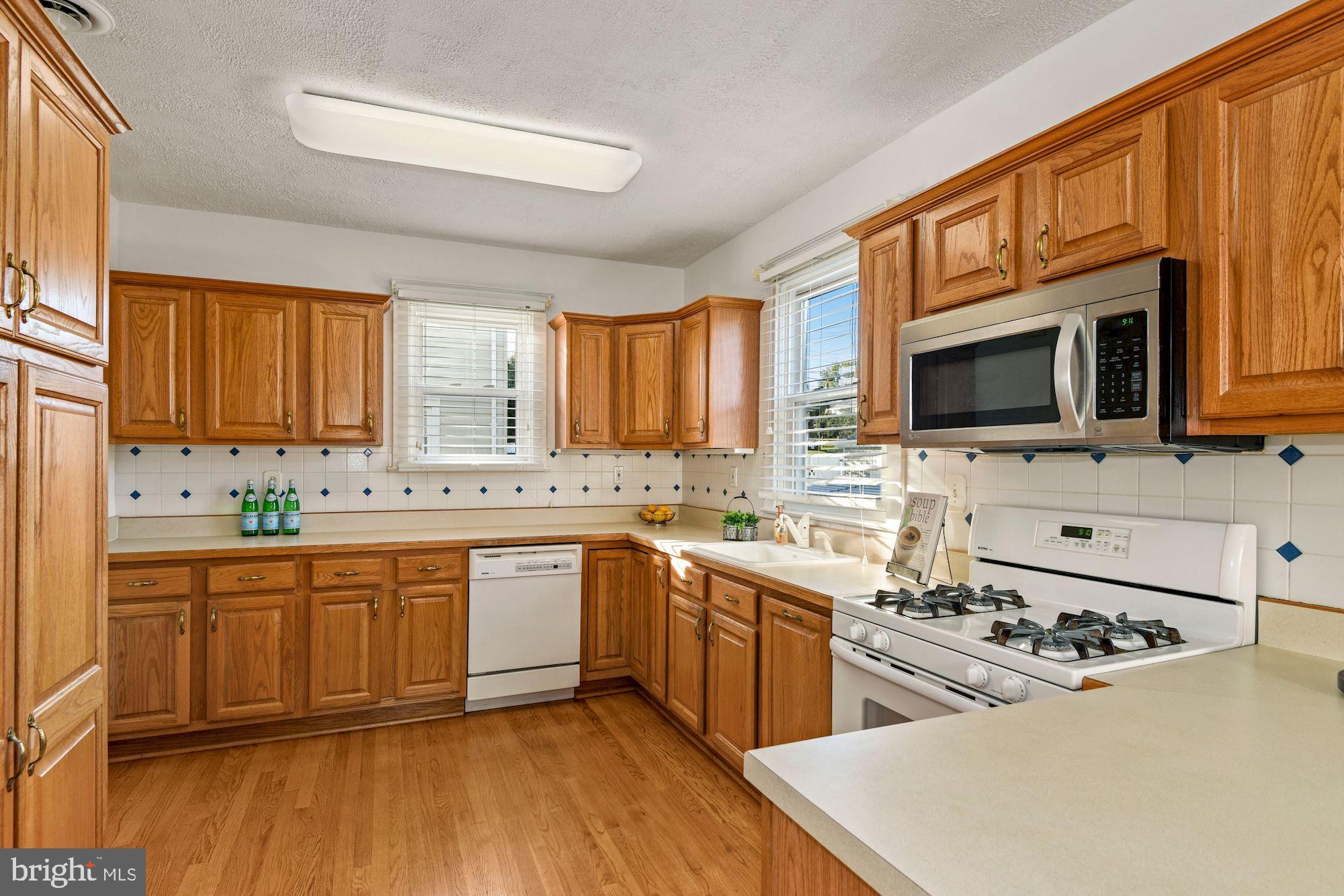 5524 Ashbourne Road Baltimore, MD 21227 - Photo 10 of 23 a kitchen with stainless steel appliances a sink dishwasher a stove top oven a refrigerator with grey cabinets and wooden floor