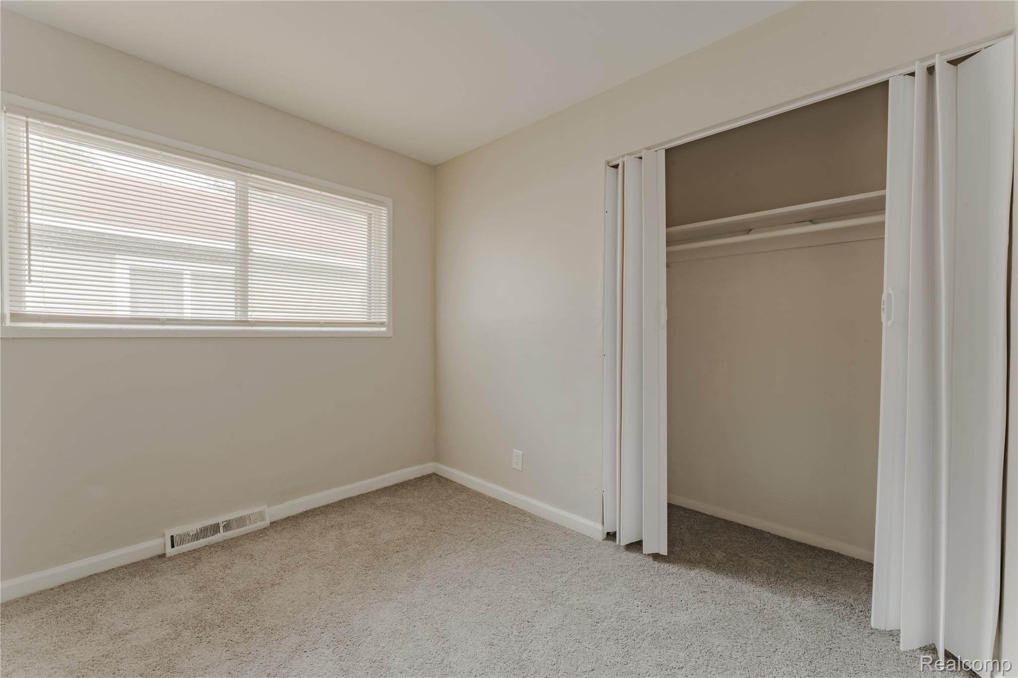 93 West Princeton Avenue Pontiac, MI 48340 - Photo 11 of 31 Carpeted room featuring a double window with blinds, bi-fold closet doors, and baseboard trim