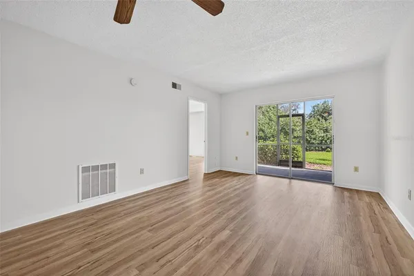 a view of an empty room with wooden floor and a window