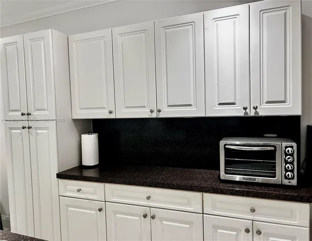 a kitchen with granite countertop white cabinets and black appliances