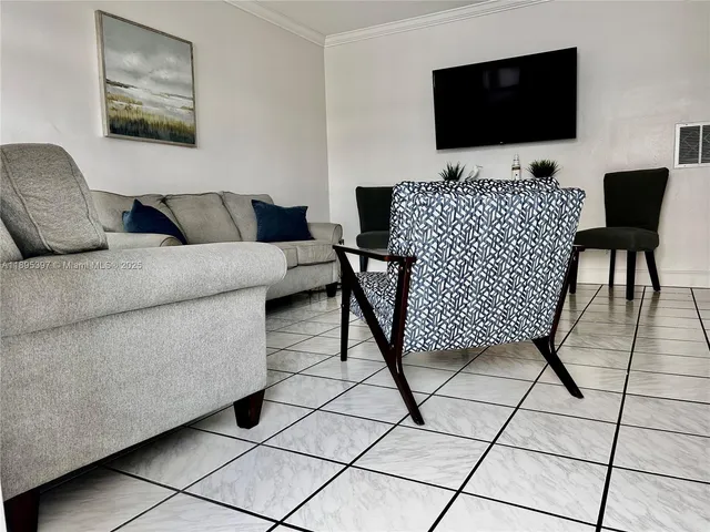 a living room with couches a flat screen tv and a lamp with rug