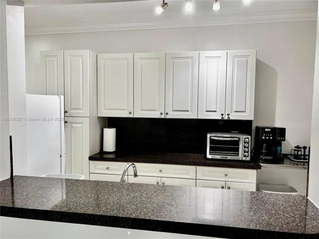 a kitchen with stainless steel appliances kitchen island granite countertop a refrigerator a stove a microwave and white cabinets