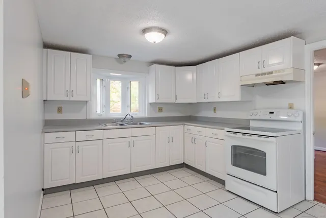 a kitchen with granite countertop white cabinets stainless steel appliances a sink and a window