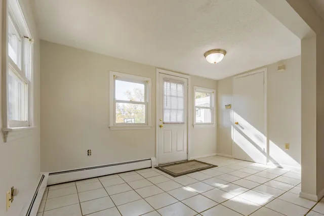 a view of an empty room with window and a refrigerator