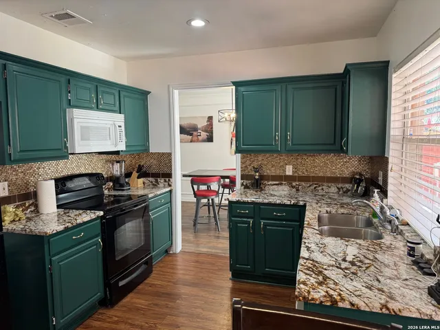 a kitchen with stainless steel appliances granite countertop a stove top oven a dining table and chairs with wooden floor