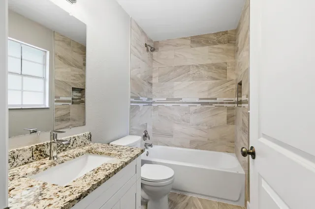 a bathroom with a granite countertop sink a toilet and shower