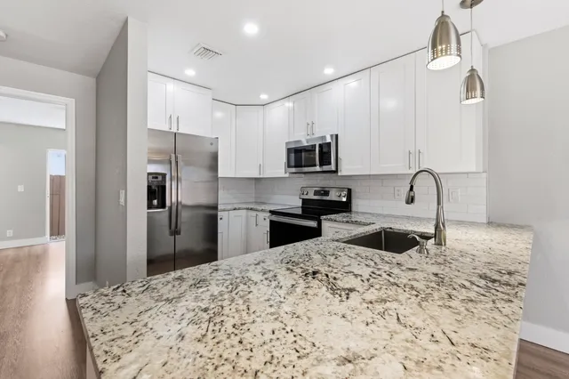 a kitchen with stainless steel appliances kitchen island granite countertop a sink refrigerator and microwave