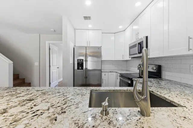 a kitchen with a refrigerator sink and cabinets