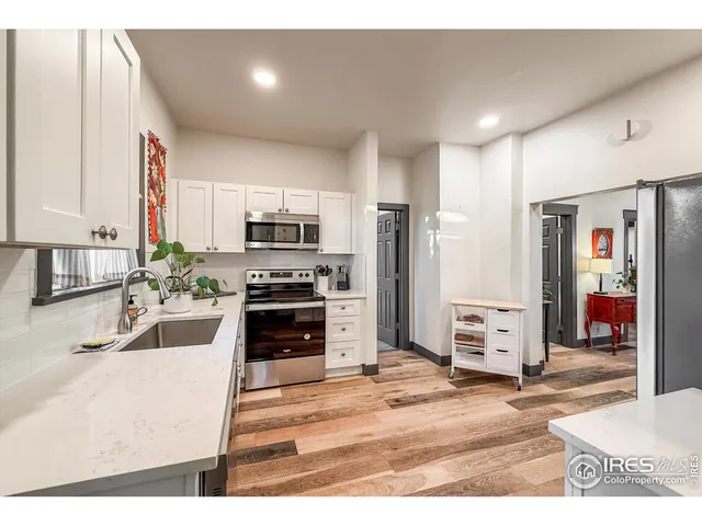 a kitchen with stainless steel appliances a stove a refrigerator a sink a oven with wooden floor